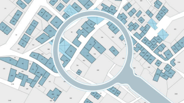 Imaginary cadastral map with buildings, land parcel and vacant plot - property registry and real estate concept seen through a magnifying glass